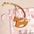 Équestre Leather Handbag Charm in brown leather shaped like a rocking horse with patterned fabric strap on pink pouch.